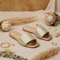 Par de rasteiras douradas caneladas em ambiente linho dourado