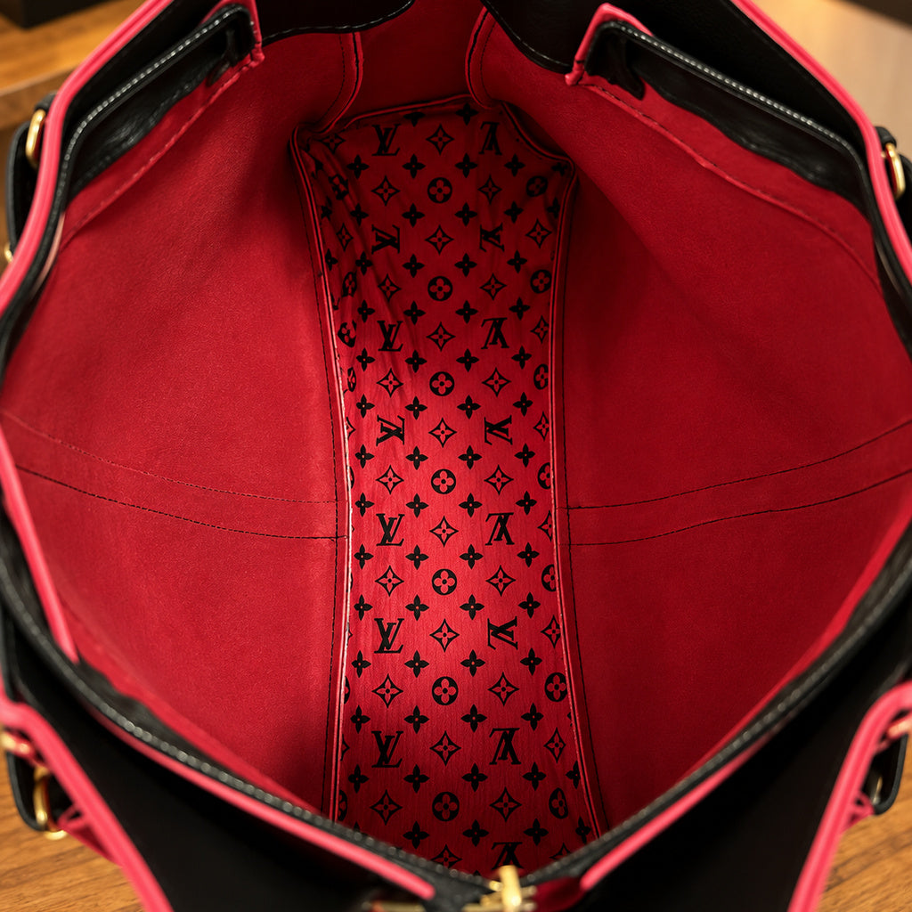 Interior da bolsa tote preta, compartimentos em vermelho e faixa central estampada